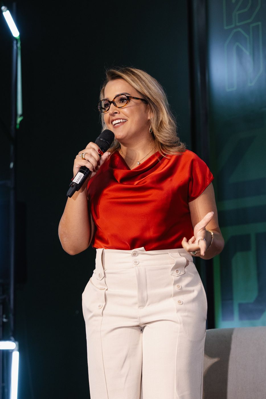 Débora Baccan falando ao microfone em um palco